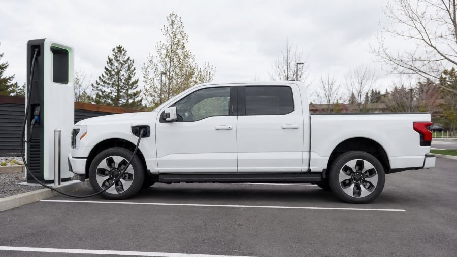 Full-size electric pickup truck connected to a public DC fast charger