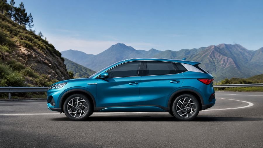 BYD Yuan Plus DM-i luxury sedan in metallic blue, side profile view on scenic mountain road