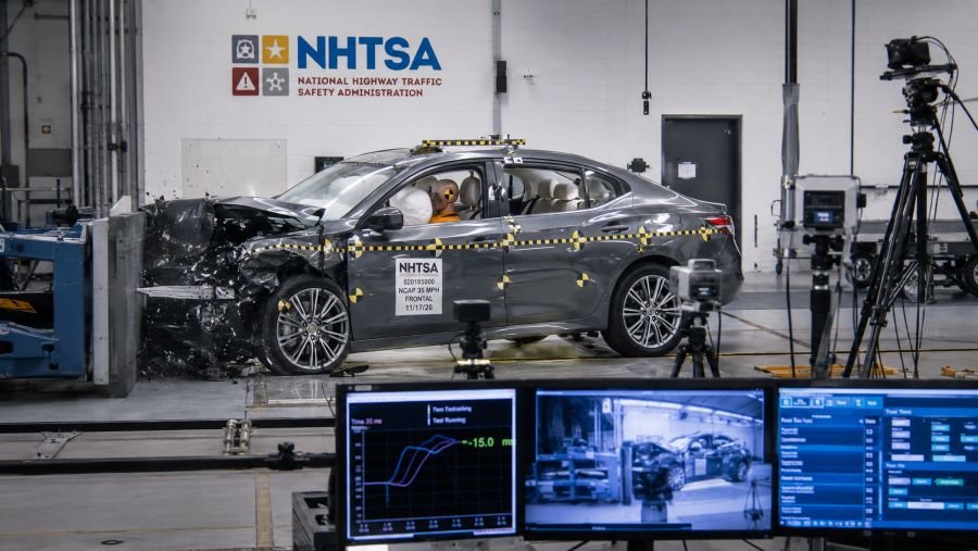 NHTSA crash testing facility with vehicle undergoing safety testing and impact measurement systems