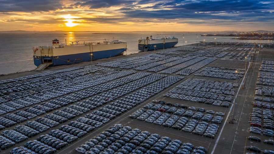 Thousands of new Chinese electric vehicles at an export port with car-carrier ships